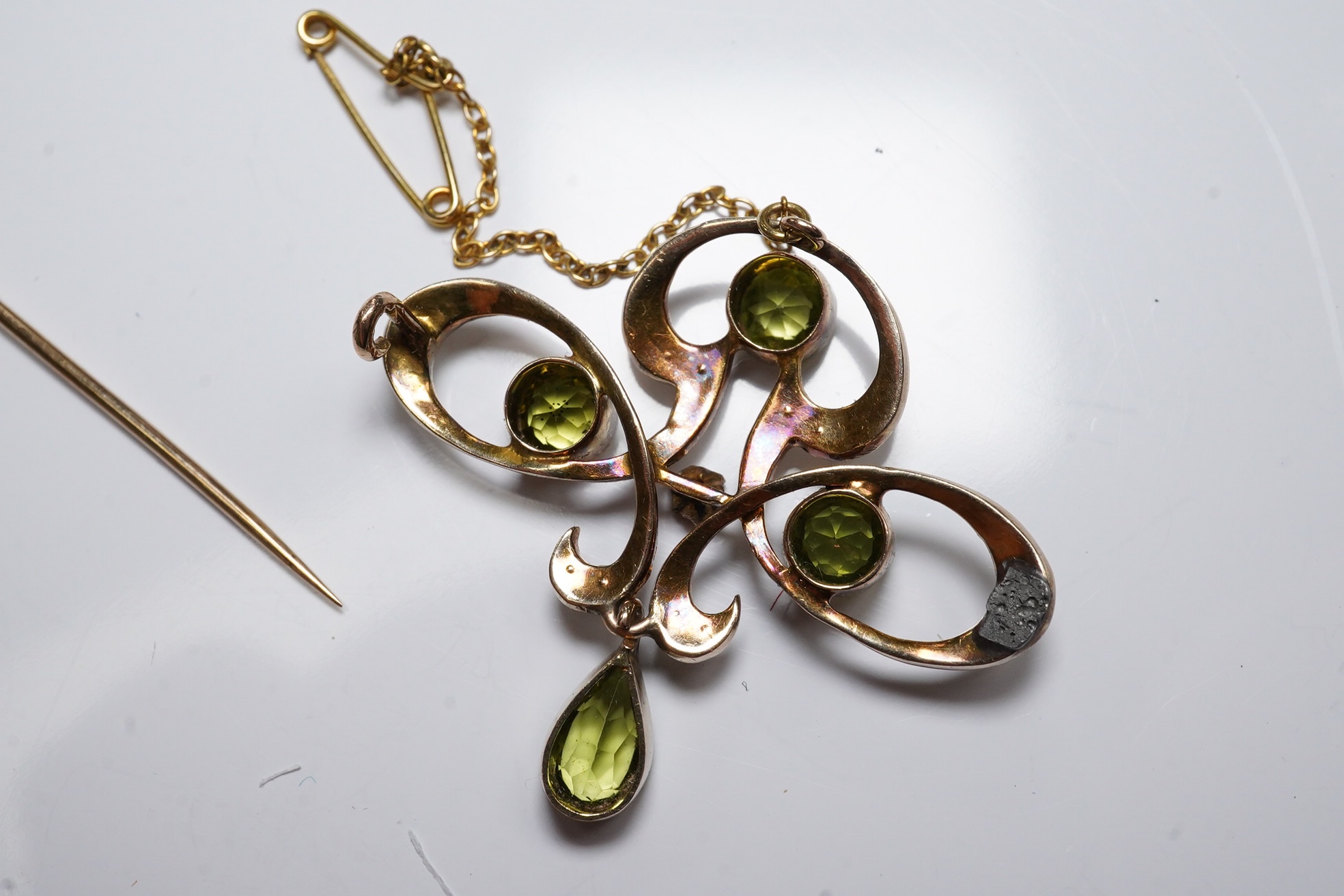 An early 20th century yellow metal, peridot, seed pearl and ruby cluster set drop pendant brooch (pin broken), width 35mm, gross weight 3.6 grams. Condition - poor